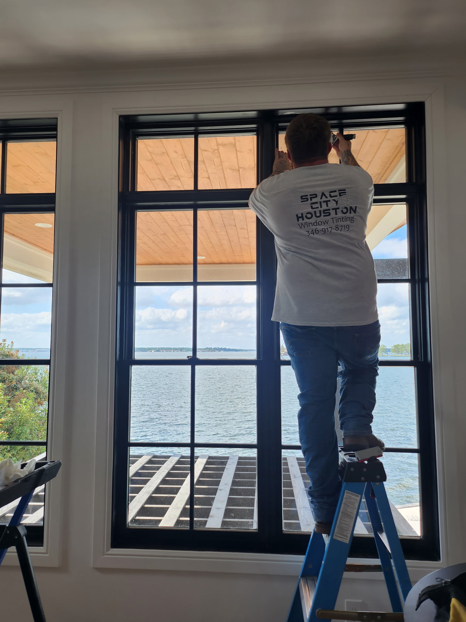 Space City Window Tinting installer applying frosted privacy film to office glass partition wall in Houston